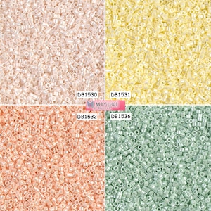 May include: Four different colors of seed beads, each in a square section. The colors are white, yellow, peach, and light green. The beads are all the same size and shape, and they are arranged in a random pattern. The text "DB1530", "DB1531", "DB1532", and "DB1536" are printed below each section. The text "MIYUKI ビーズ＆クラフト" is printed in the center of the image.
