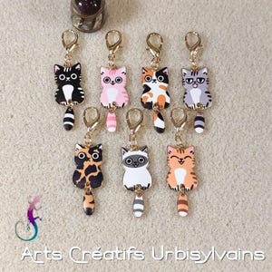 Peut inclure: Collection de sept porte-clés en forme de chat de différentes couleurs, dont noir, rose, orange et gris. Chaque porte-clés est doté d'un fermoir doré et d'un charm pendant. Les porte-clés sont conçus avec des visages et des motifs de chats de style dessin animé.