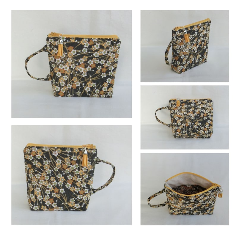 May include: A black and gold zippered pouch with a floral pattern and a small tassel. The pouch has a handle and can be used as a small bag.