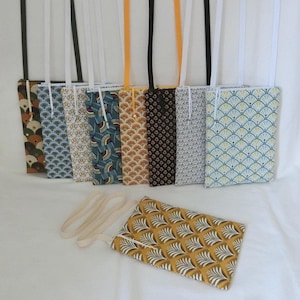 Può includere: Una collezione di borse a tracolla rettangolari in tessuto con vari motivi, tra cui disegni a ventaglio e floreali, e lunghe cinghie. Una borsa è piatta in primo piano. Le borse presentano colori come marrone, blu, giallo e bianco.