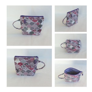 May include: A small purple zippered pouch with a white background and a colorful pattern of fans and circles. The pouch has a purple handle and a gold tassel.