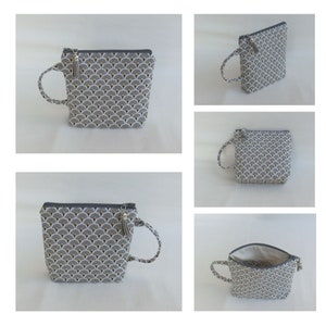 May include: A gray and white zippered pouch with a gold and white geometric pattern. The pouch has a gray tassel and a gray loop handle.
