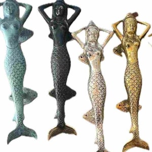 Puede incluir: Cuatro tiradores de puerta decorativos de sirena en diferentes acabados: verde azulado, negro, plateado y dorado. Cada tirador presenta una sirena con las manos detrás de la cabeza y una cola de pez detallada.