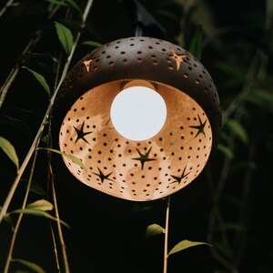 Carved coconut lamp glowing warm light, handmade coconut shell pendant lamp decor