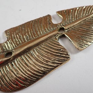 Macro close up of hand textured brass leaf hook surface showing detailed vein and leaf pattern engraving