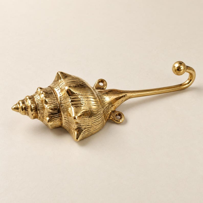 Front view of brass shell spiral hook standing upright on a cream background