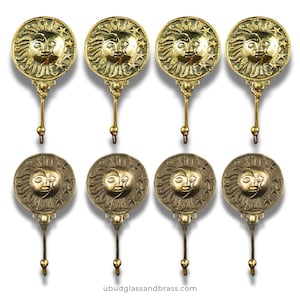 Puede incluir: Ocho perchas de pared de latón con un diseño de cara de sol y luna. Cada gancho presenta una cara circular con un sol y una luna sonrientes, rodeados de estrellas. Los ganchos son de latón y tienen un estilo decorativo y vintage.