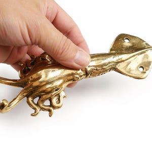 Brass squid wall hook held in hand showing size and handmade Bali craftsmanship