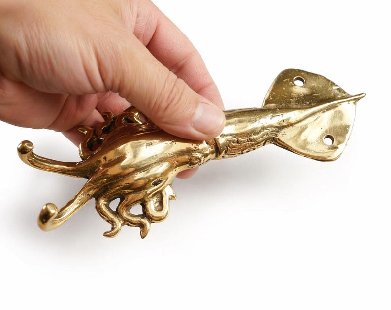 Brass squid wall hook held in hand showing size and handmade Bali craftsmanship