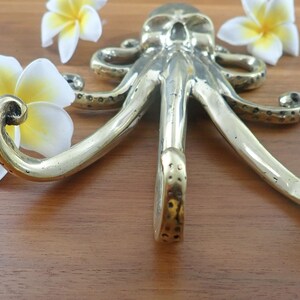 Brass octopus wall hook lying on wood table, kraken coat hook nautical brass decor