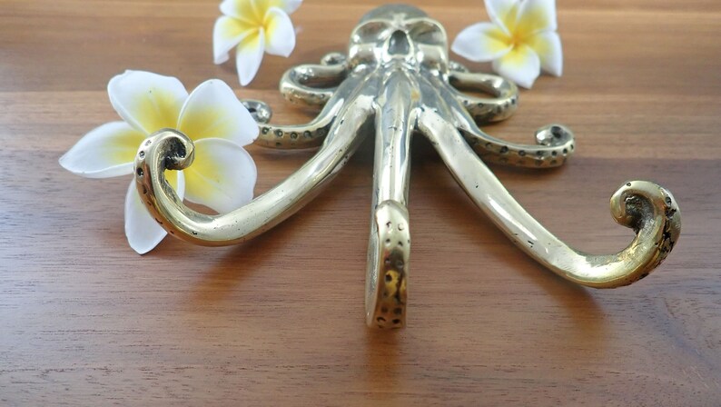 Brass octopus wall hook lying on wood table, kraken coat hook nautical brass decor