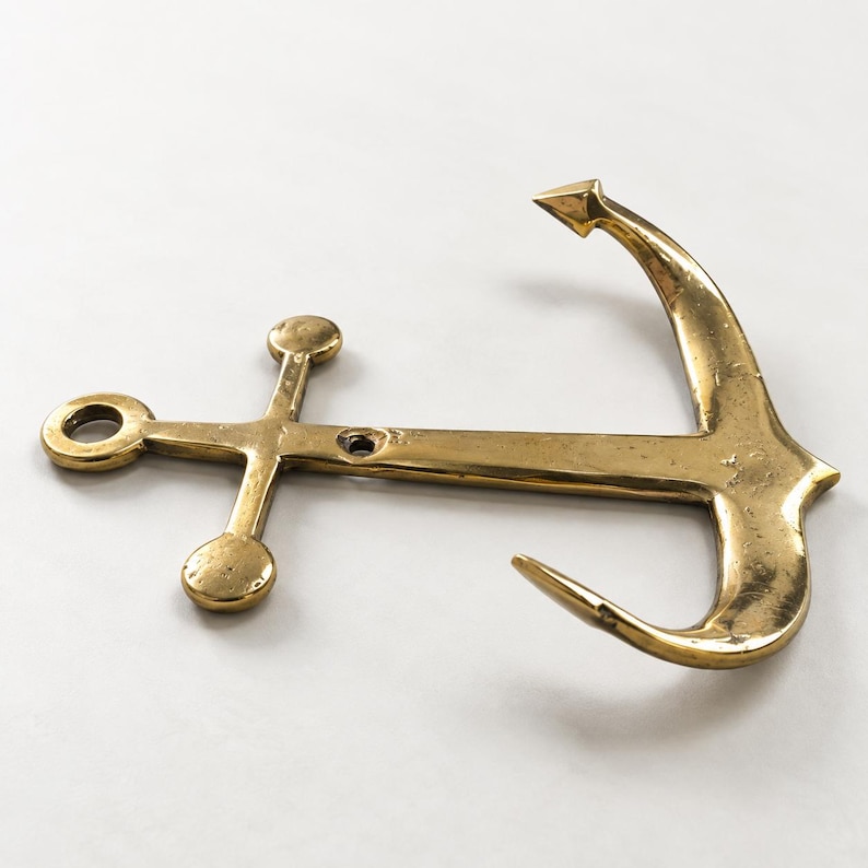 Brass anchor wall hook in an antique brass finish on a white background, angled view showing anchor shape and hook detail