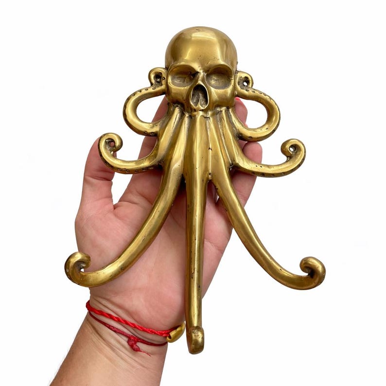 Hand holding brass octopus hook showing size, kraken wall hook nautical brass coat hanger