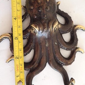 Measuring brass octopus wall hook showing real product size and scale