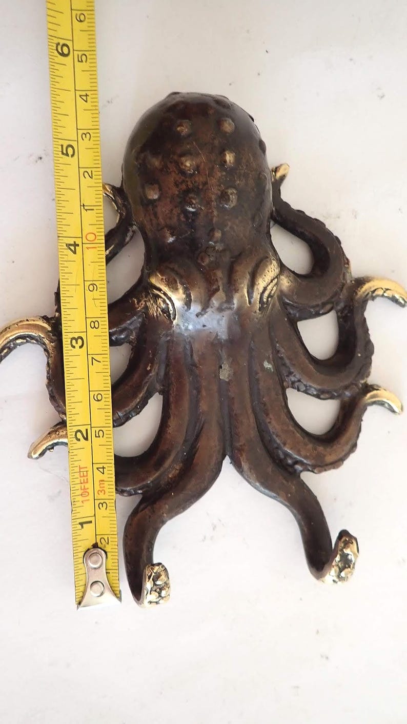 Measuring brass octopus wall hook showing real product size and scale