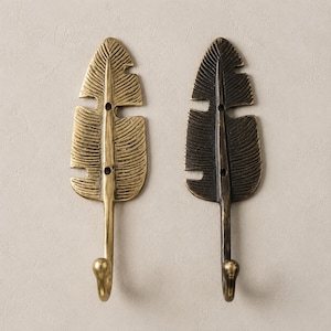 Two brass banana leaf hooks side by side showing antique bronze finish and polished brass finish options