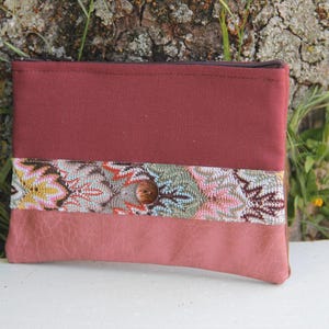 Peut inclure: Une pochette zippée bordeaux avec une bordure en tissu à motifs floraux et un fond en daim bordeaux.