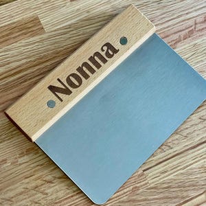 May include: A wooden-handled stainless steel dough scraper with the word "Nonna" engraved on the handle.