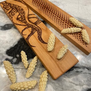 May include: Two wooden serving boards with a decorative design. One board features a detailed illustration of an octopus, while the other has a repeating pattern of circles.  The boards are surrounded by small, white, textured, food items.