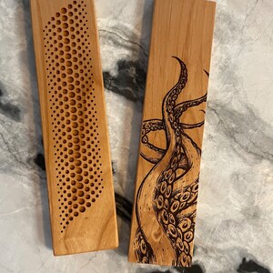 May include: Two wooden coasters with different designs. One coaster features a geometric pattern of circles, while the other has a detailed illustration of an octopus.