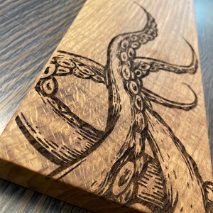May include: A wooden cutting board with a burned-in design of an octopus tentacle.
