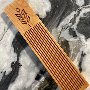 May include: A wooden bread board with a wheat design and grooves for cutting bread.