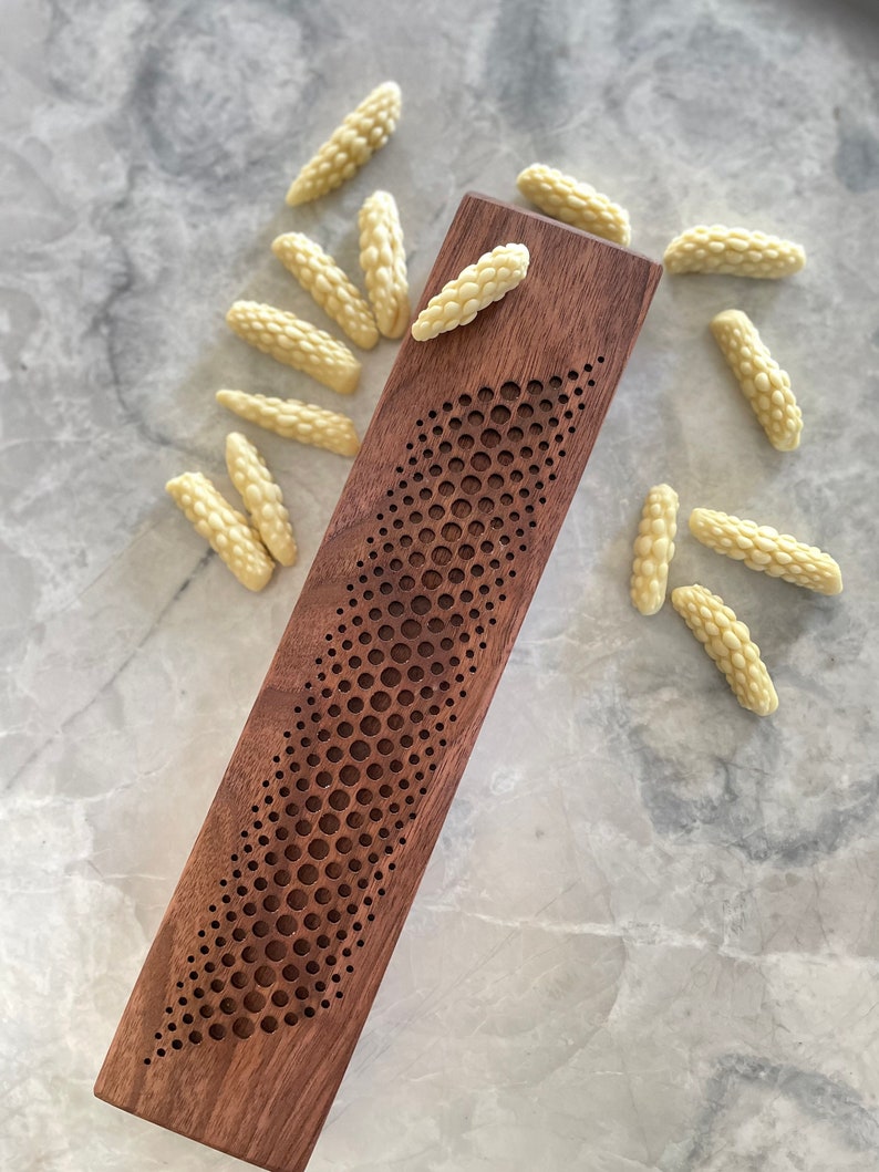 May include: A wooden incense holder with a geometric pattern and a pile of white incense sticks.