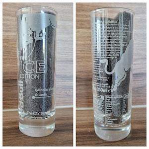 May include: A clear glass with the text "THE ICE EDITION" and the Red Bull logo. The glass is filled with a dark substance. The text "ENERGY DRINK" is also visible.