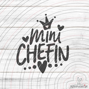 May include: Black graphic design with the words "Mini CHEFIN" in a playful font, crowned with a small crown and hearts. The design is set against a white wood-grain background with curved lines.