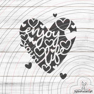 May include: A black heart-shaped design with the words "enjoy your life" in a cursive font. The heart is filled with smaller heart shapes and surrounded by several small hearts. The background is a white wood grain pattern.