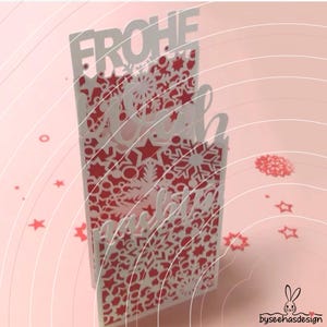 May include: A vertical greeting card featuring a white laser-cut overlay with intricate snowflake and star patterns over a solid red background. The top of the card displays the text FROHE in white block letters, with additional script text below.