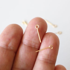 May include: Gold-toned head pins with a loop at the top. The pins are approximately 2.5 cm long.