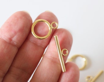 May include: Gold-toned metal toggle clasp with a round ring and a straight bar. The clasp is designed for jewellery making and crafting.