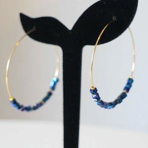 Puede incluir: Aretes de aro dorados con cuentas cuadradas azules iridiscentes.