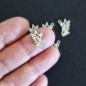 Peut inclure: Charmes en métal argenté en forme d'ange agenouillé avec des ailes. Les charmes ont un trou en haut pour être attachés à des bijoux ou d'autres objets artisanaux.