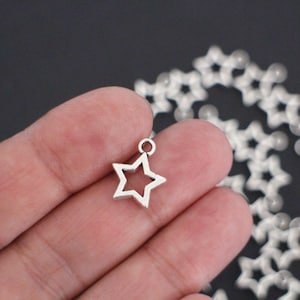 10 ihåliga stjärnberlocker i försilvrad metall, 15 x 12 mm