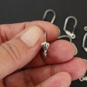 Peut inclure: Crochets d'oreille en argent avec un design décoratif en forme d'éventail. Les crochets sont conçus pour être utilisés avec une variété de boucles d'oreilles.