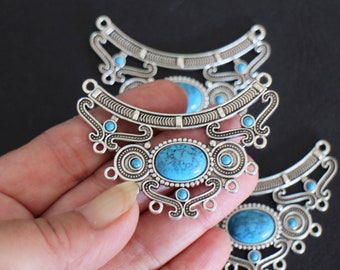A half-moon shaped connector worked with round and oval cabochon arabesques in turquoise acrylic and silver-plated brass 64 x 47 mm