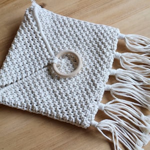 以下が含まれることがあります： 木製のリングハンドルとフリンジのトリムが付いた白いクロシェバッグ