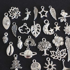 May include: A collection of silver charm pendants featuring various designs, including leaves, stars, moons, clouds, flowers, and more. These charms are perfect for adding a personal touch to jewelry projects.