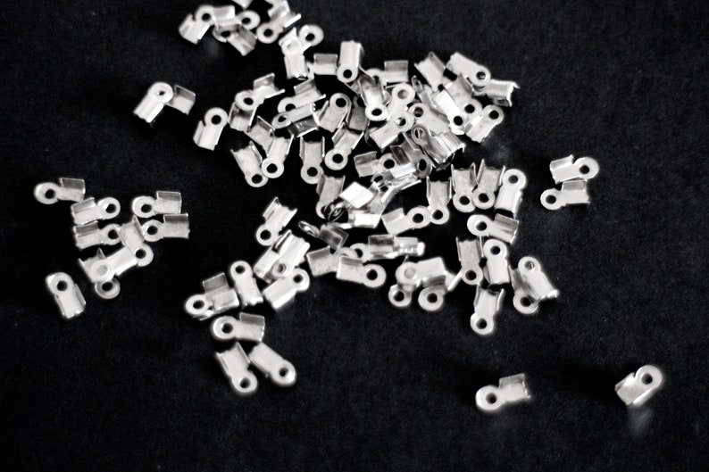 May include: A pile of silver-toned metal crimp beads, used for jewelry making.