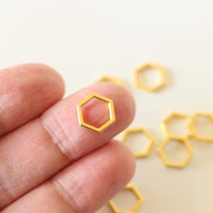 May include: Gold-toned metal hexagon jump rings. The rings are small and have a smooth, polished finish.