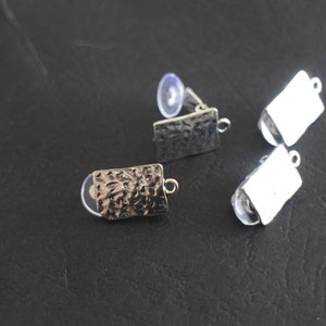 May include: Three silver earring blanks with a textured finish. Two of the blanks are smooth and one has a hammered texture.