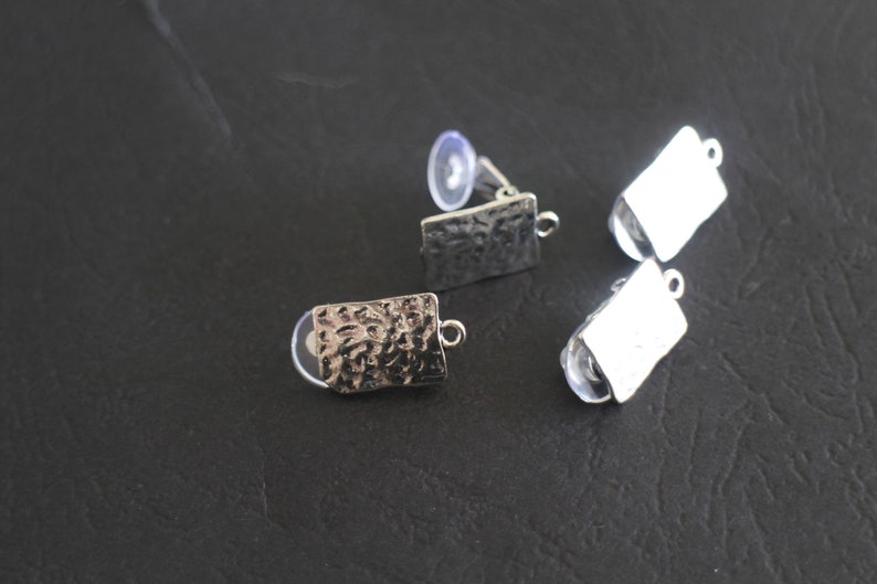 May include: Three silver earring blanks with a textured finish. Two of the blanks are smooth and one has a hammered texture.