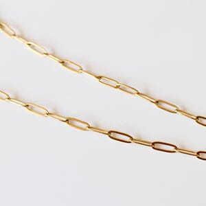 Puede incluir: Un collar de cadena en tono dorado con eslabones ovalados rectangulares alargados conectados en una serie continua. Los eslabones met&aacute;licos tienen una superficie pulida y reflectante, creando un patr&oacute;n uniforme y repetitivo.