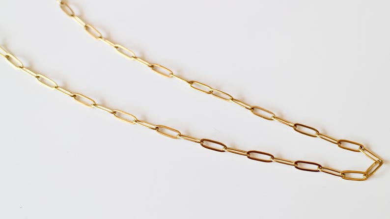 Puede incluir: Un collar de cadena en tono dorado con eslabones ovalados rectangulares alargados conectados en una serie continua. Los eslabones met&aacute;licos tienen una superficie pulida y reflectante, creando un patr&oacute;n uniforme y repetitivo.