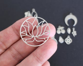 May include: A collection of silver-colored metal charms, including a circular lotus flower pendant, a crescent moon, and various other shapes. The charms are displayed against a dark background, showcasing their intricate designs and details.