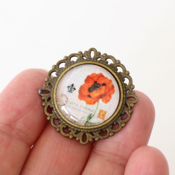 Une broche ronde coquelicot en verre et laiton bronze dentelé Fait-main