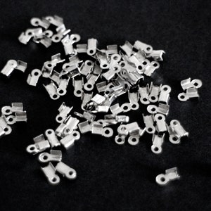 May include: A pile of silver metal crimp end caps for jewelry making.