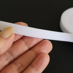 May include: White hook and loop tape, also known as Velcro, is shown in a close-up image. The tape is soft and flexible, and it is perfect for a variety of craft and sewing projects.